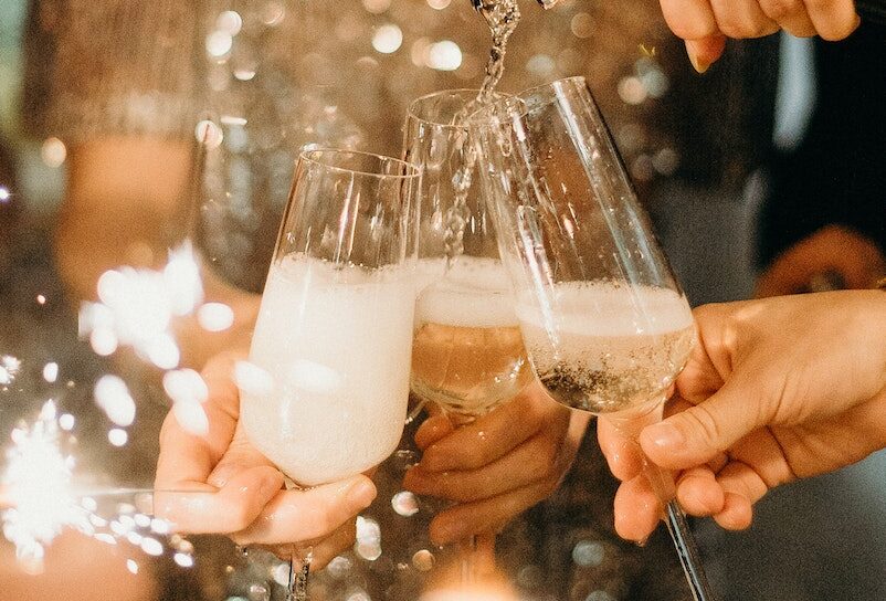 Person Pouring Champagne on Champagne Flutes