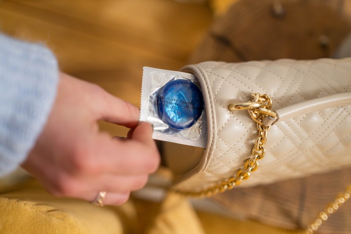 Close-Up Shot of Person Holding a Blue Condom in a Pack