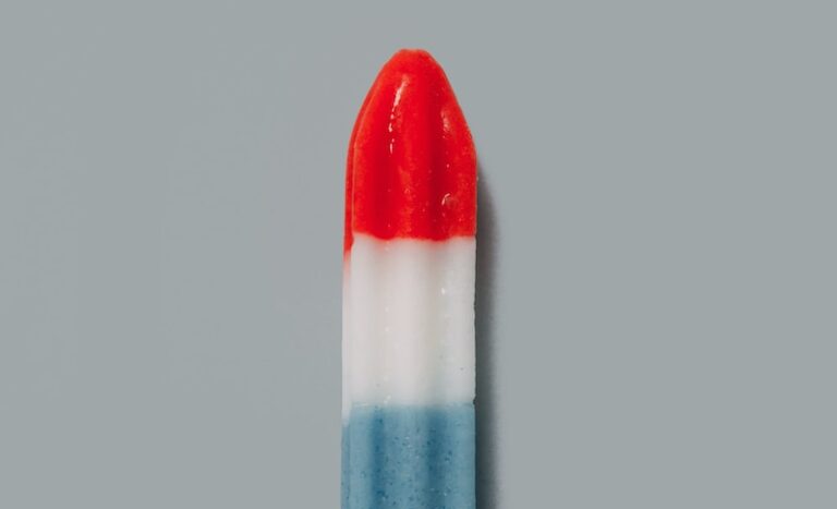 red, white, and blue popsicle on beige surface