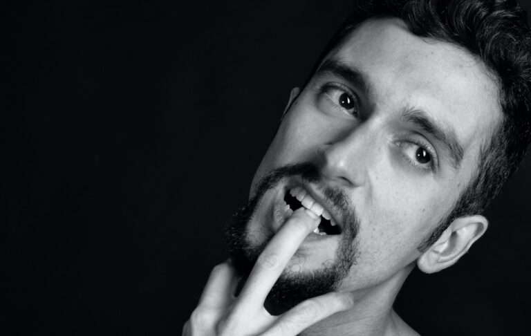 grayscale photography of man biting his finger